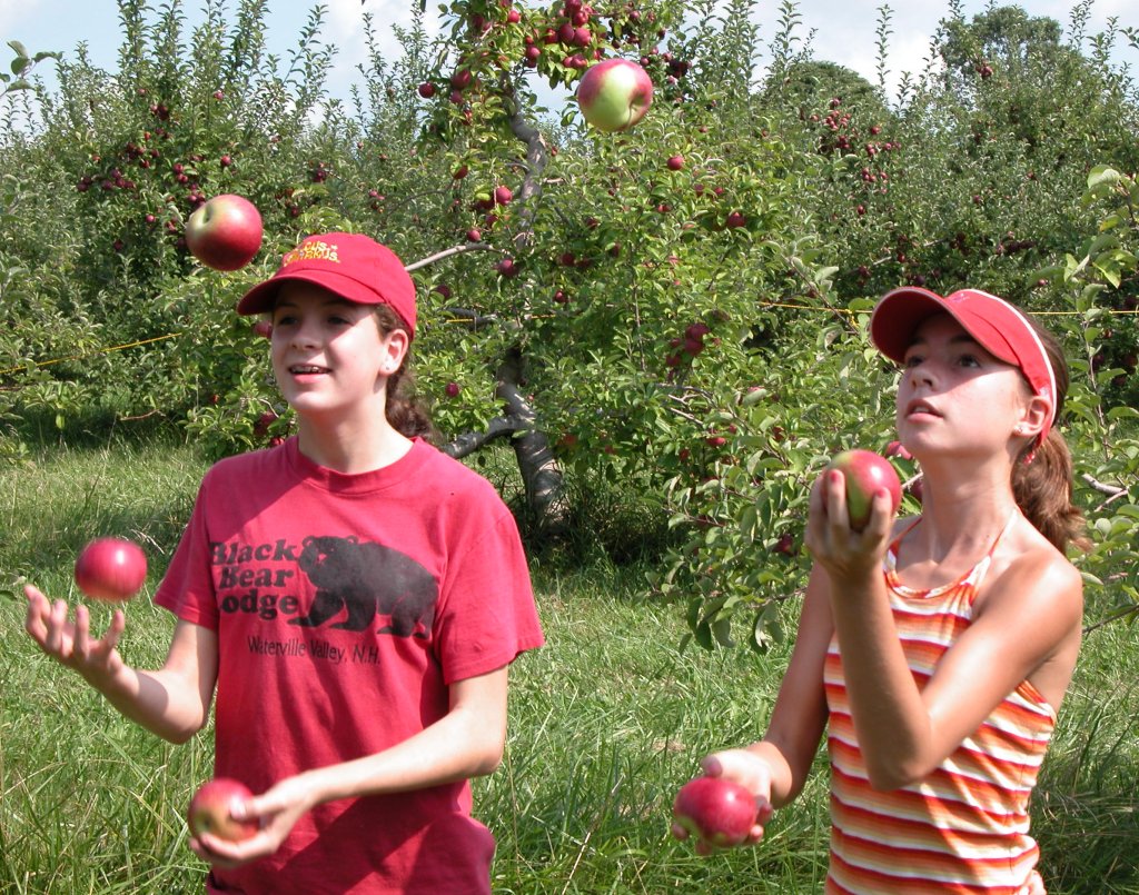 Circus girls juggle apples they've picked.